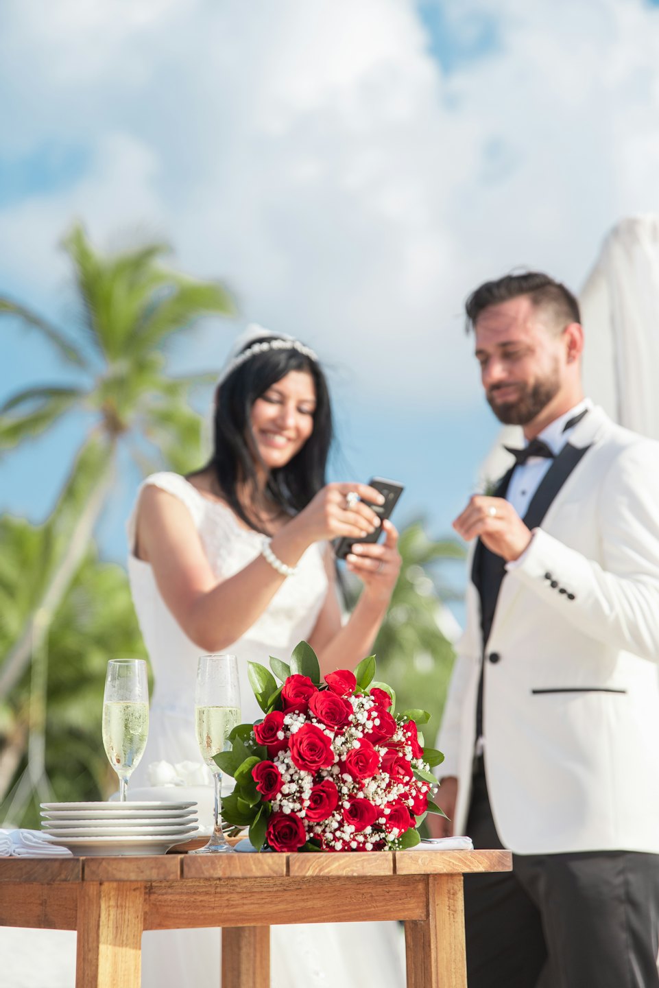 Recién casados se toman una selfie en una mesa con rosas.